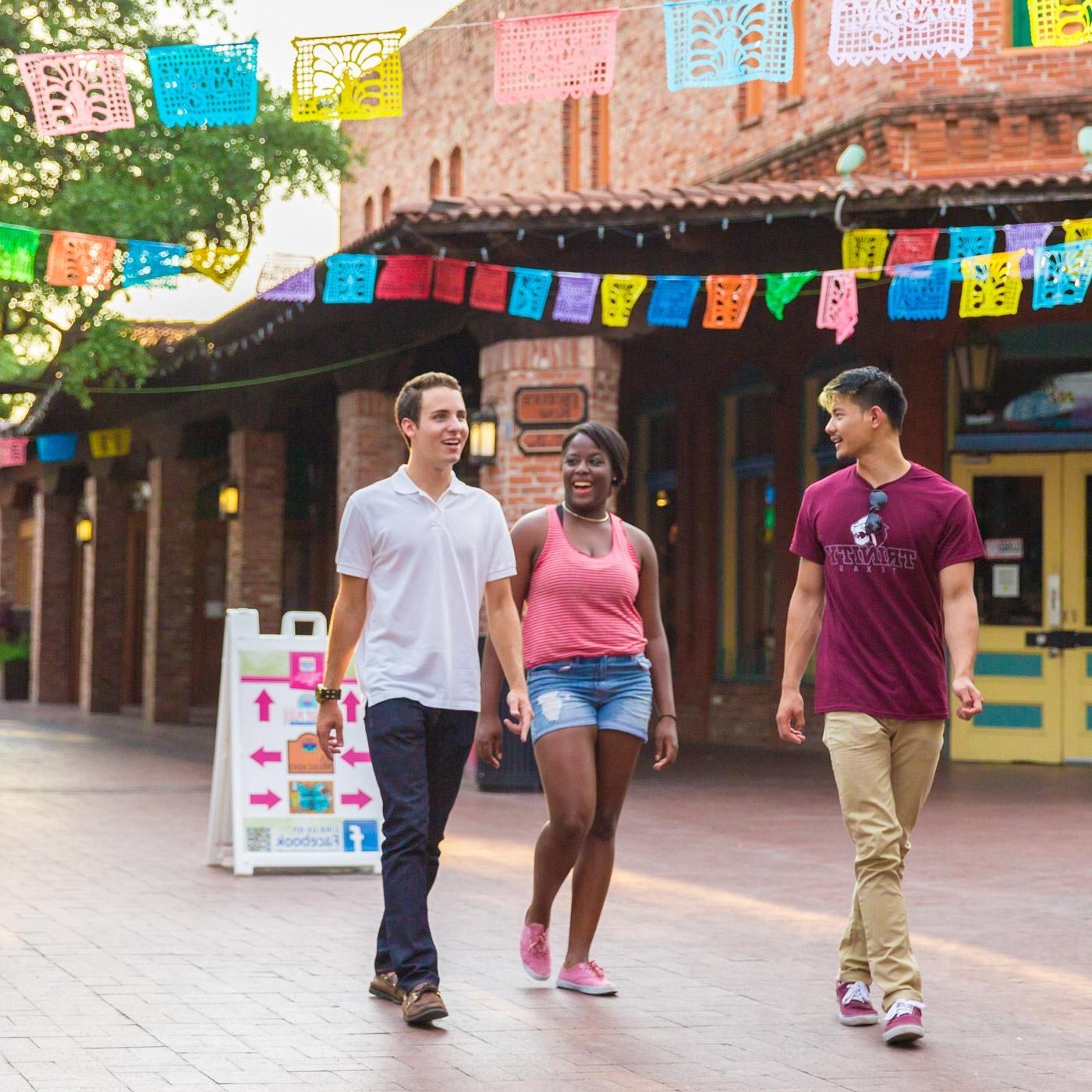 three 滚球网站 students walk through Market Square under papel picado